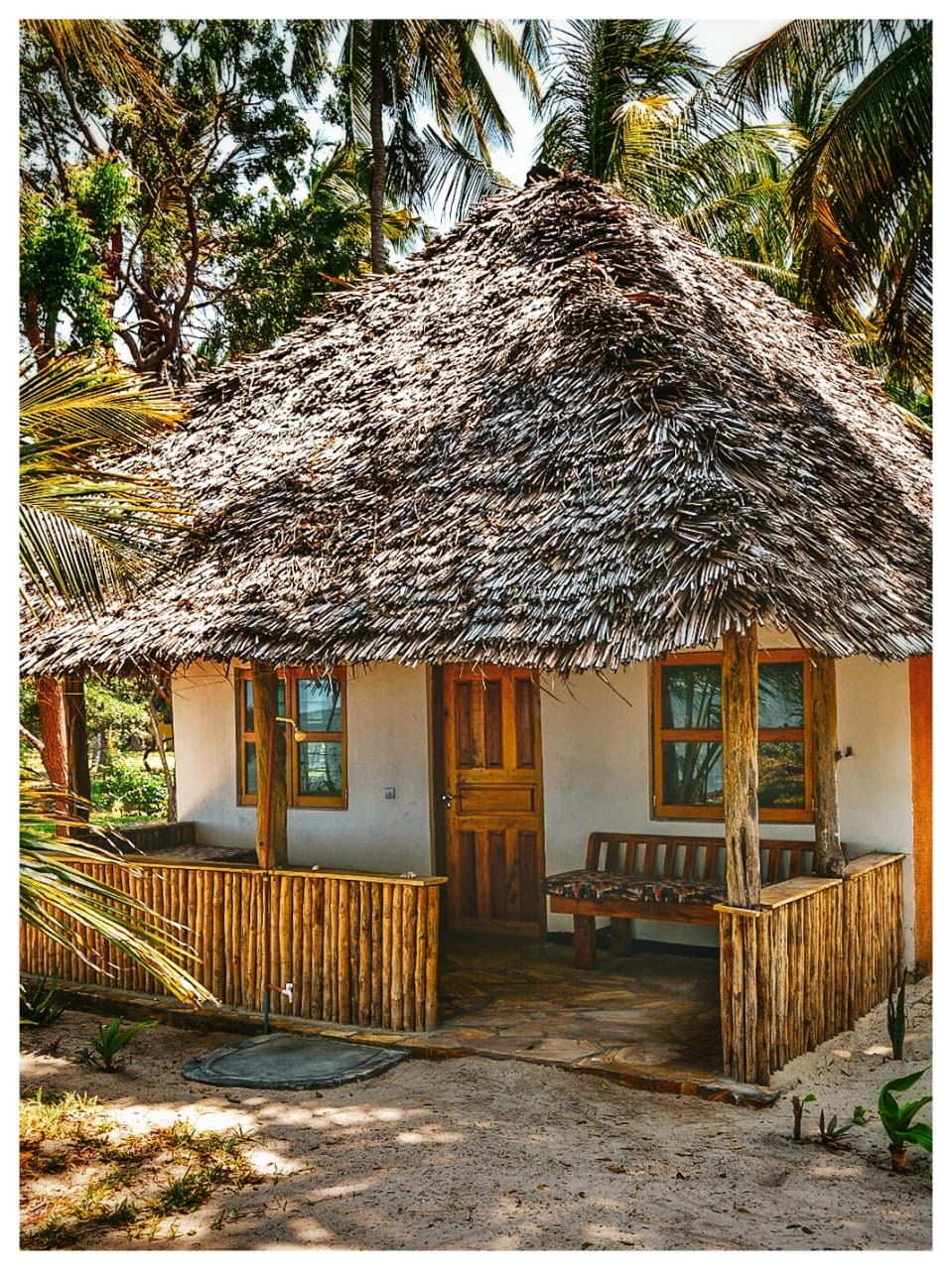 Mawimbi bungalow with makuti roof and wooden veranda among palms