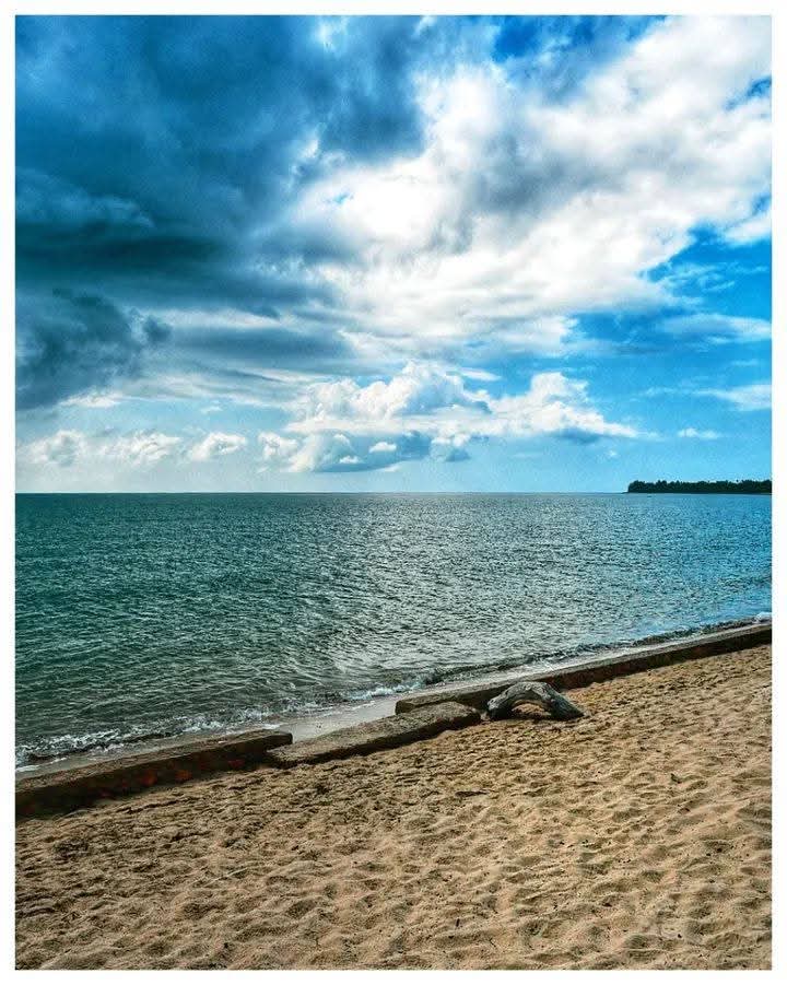 Wide sandy beach and a driftwood log under a dramatic cloudy sky