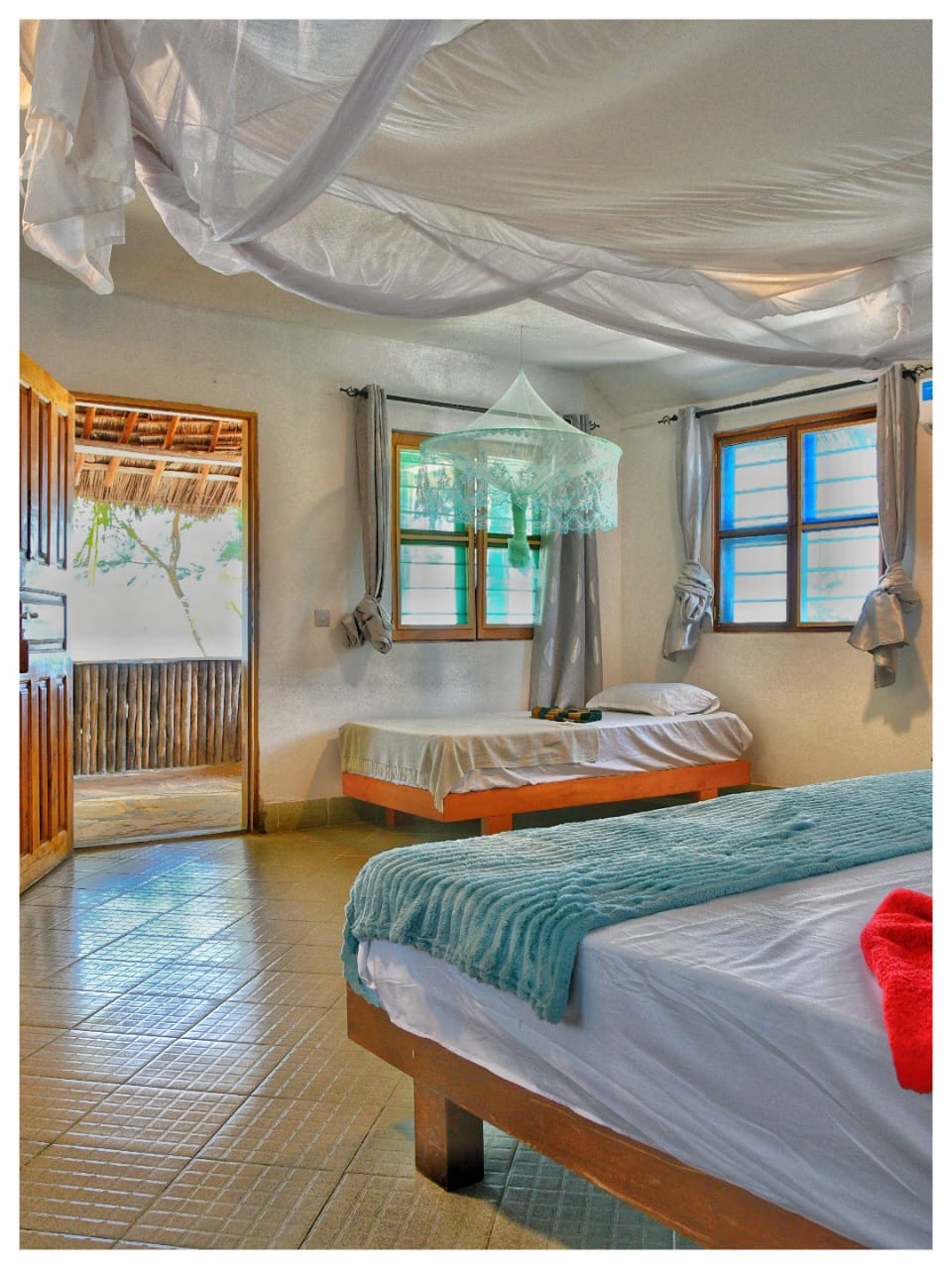Double bed and extra single bed under mosquito nets in Mawimbi