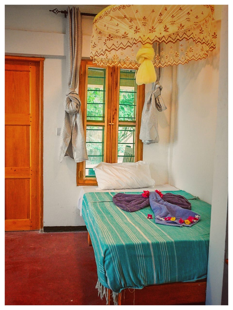 Bed with turquoise throw and folded towels in Nanga