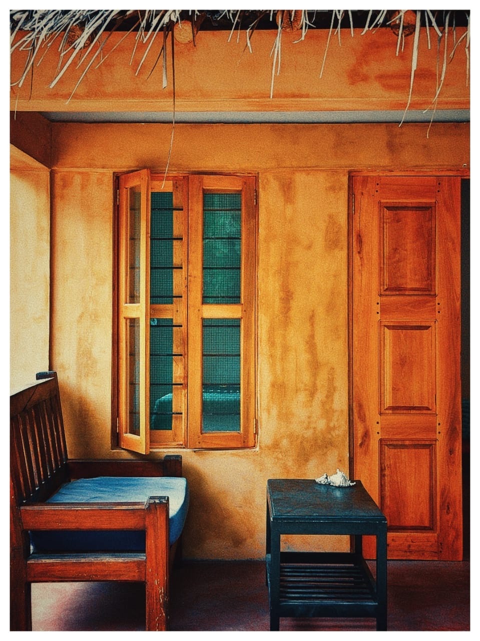 Shaded veranda with wooden bench and shell table at Nanga