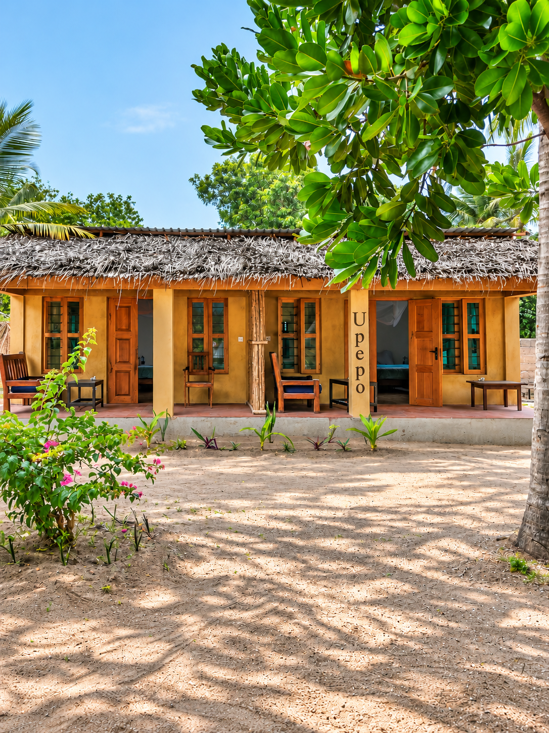 Upepo bungalow with makuti roof and ochre veranda among trees