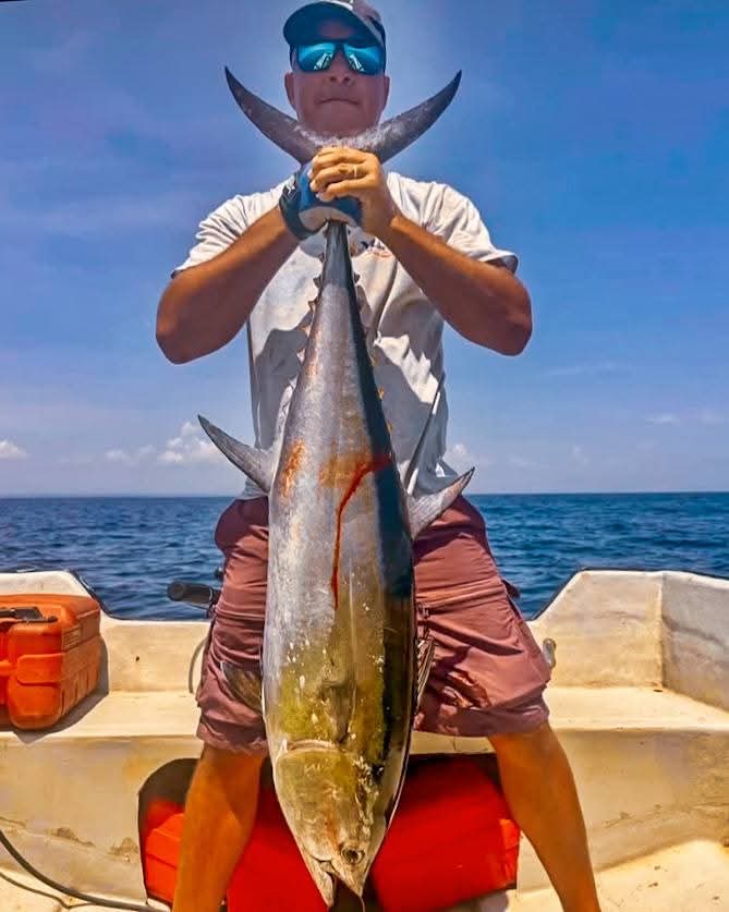 Guest on a fishing boat holding a large tuna caught off Ushongo