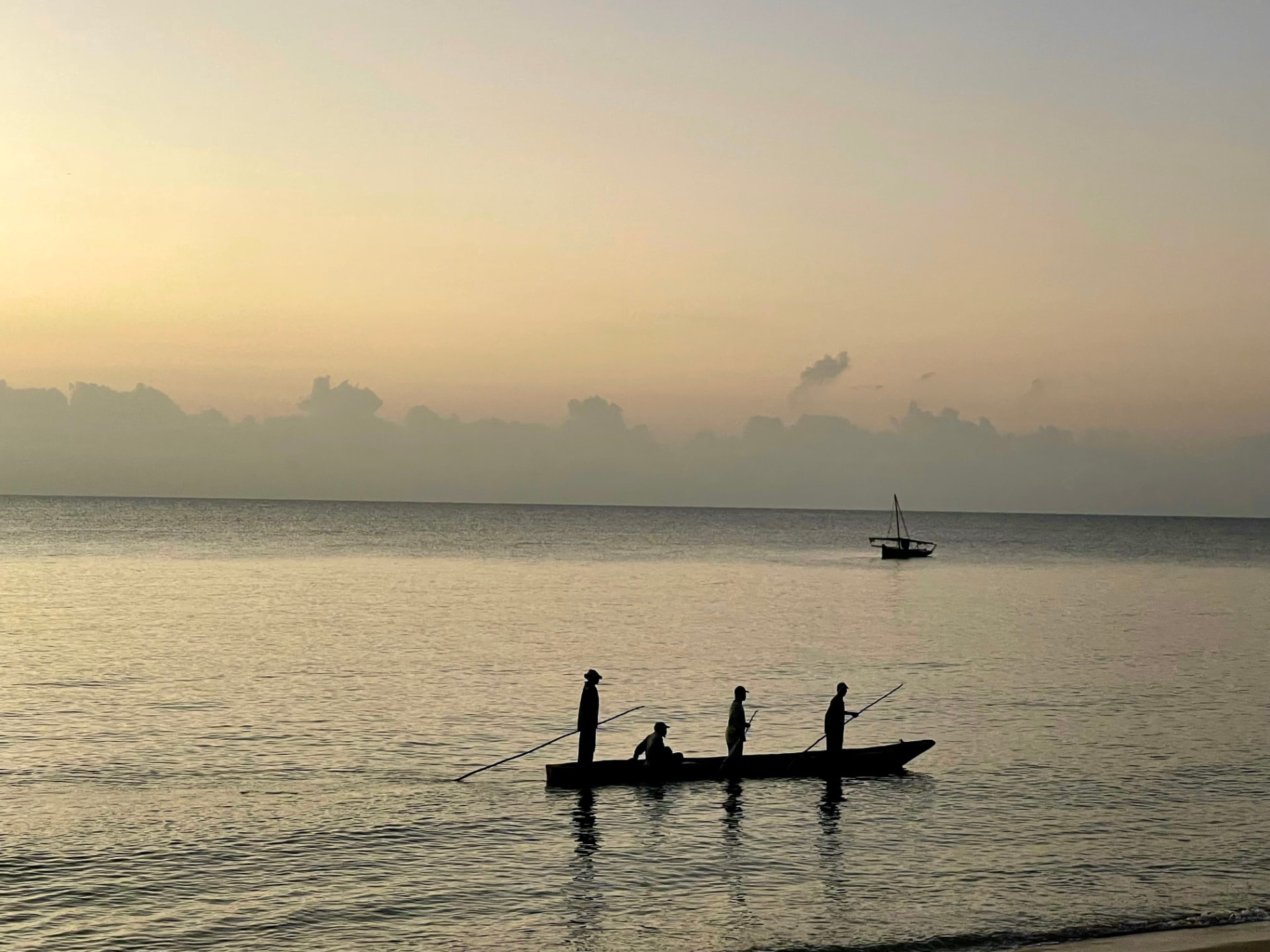 Fishermen standing in a dugout canoe at dawn off Ushongo Beach