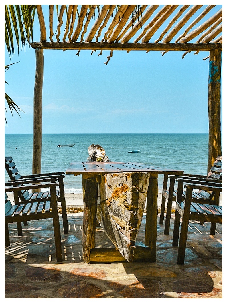Driftwood table under a pergola with an open view of the Indian Ocean