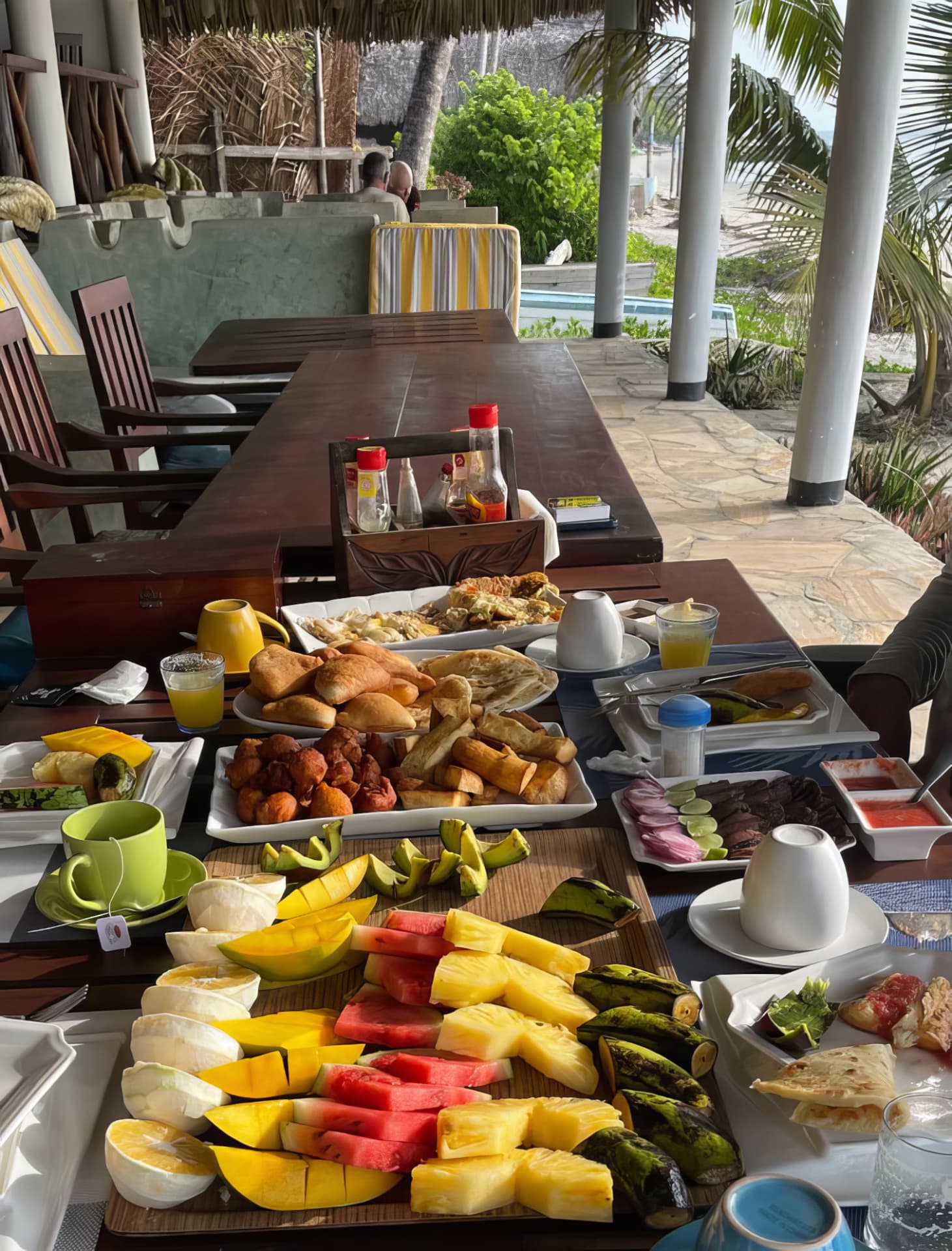 Breakfast table laid with tropical fruit, mandazi and fresh juice