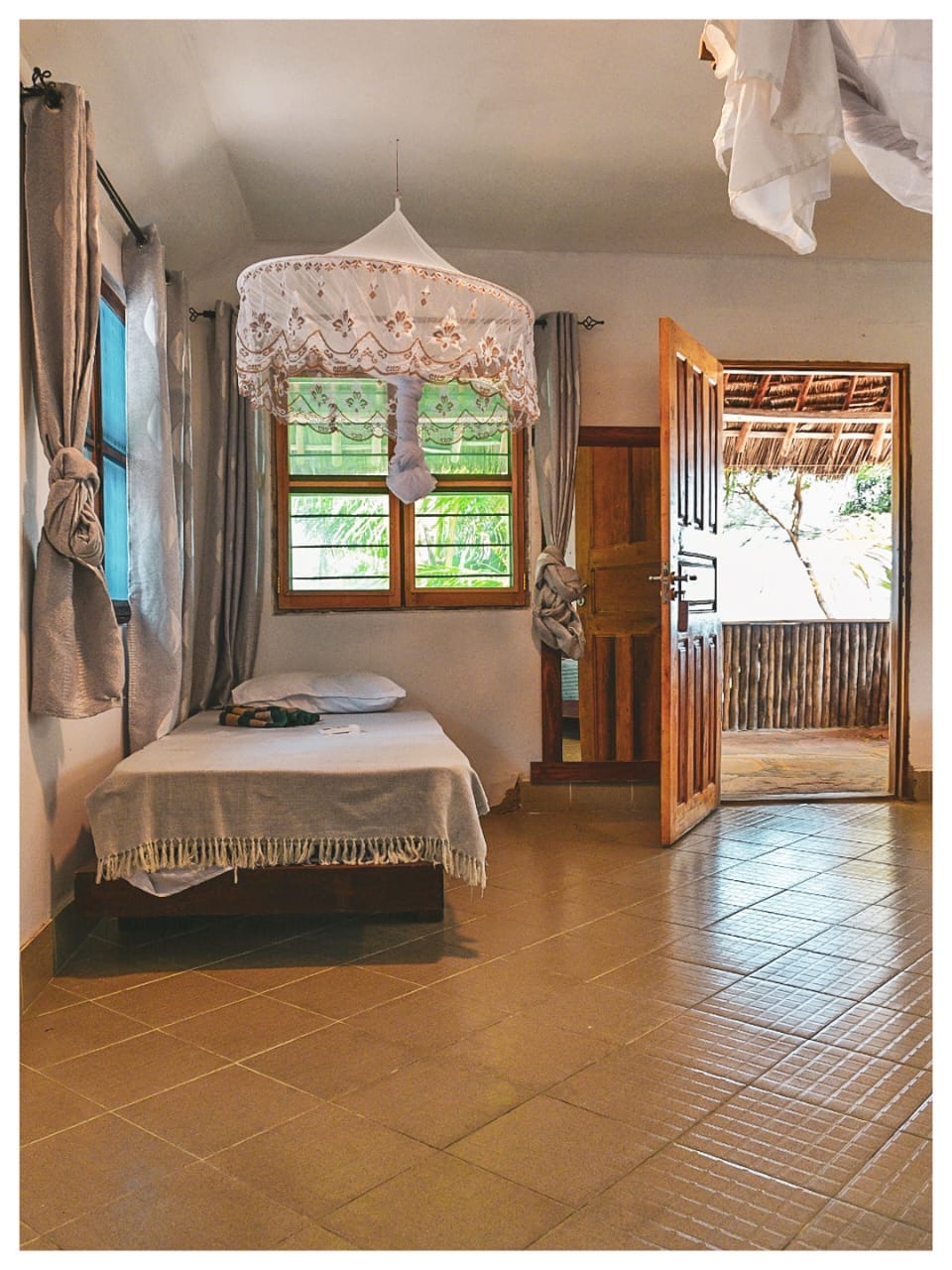 Bright bedroom in Mawimbi with extra bed and open door to the veranda
