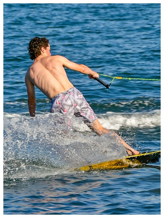 Water skier carving through blue water behind the boat