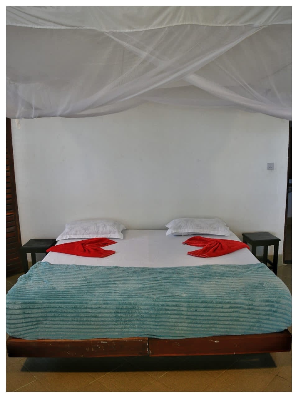 Double bed with mosquito net inside the Mawimbi bungalow